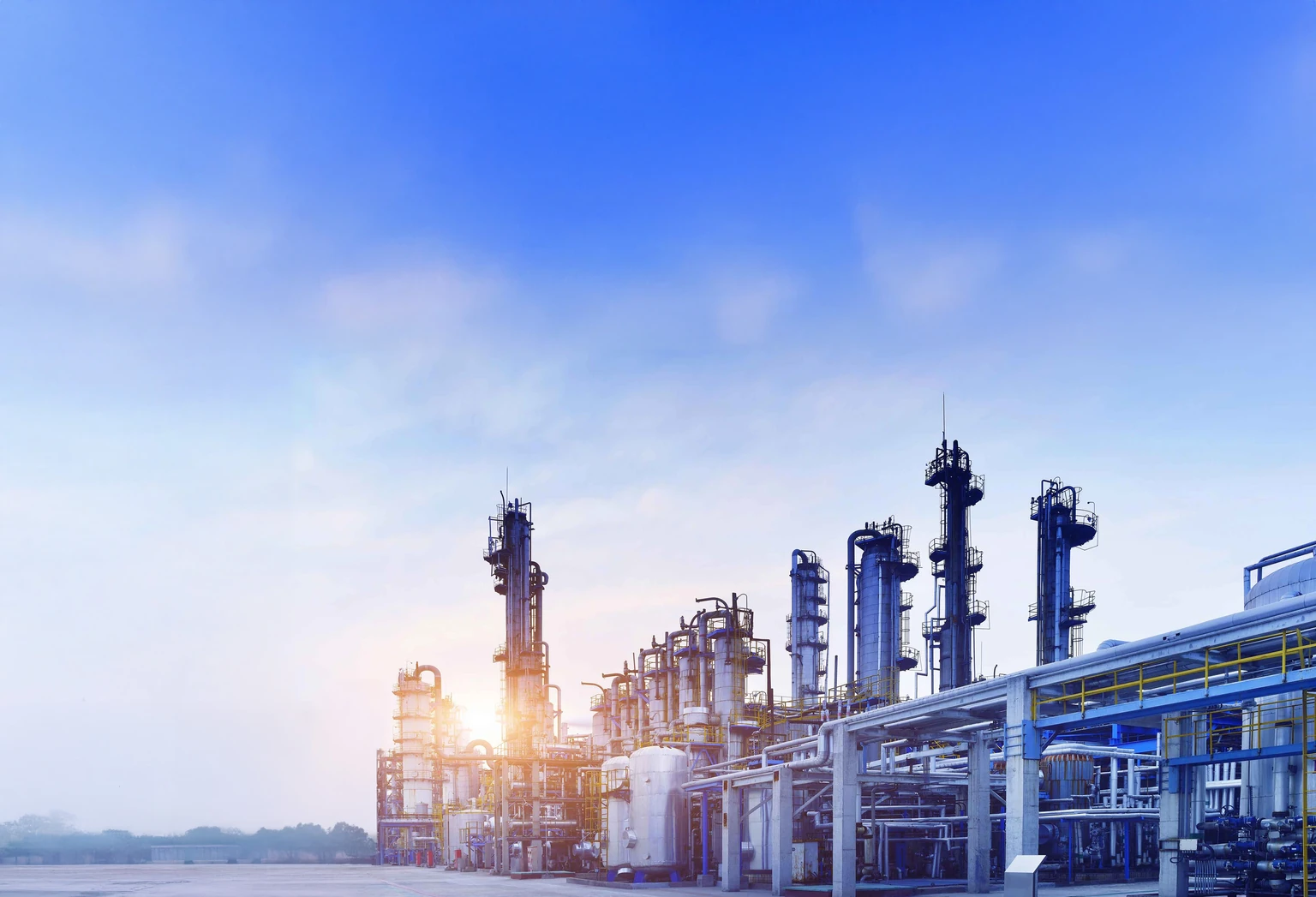Industrial processing columns and pipework in early morning light