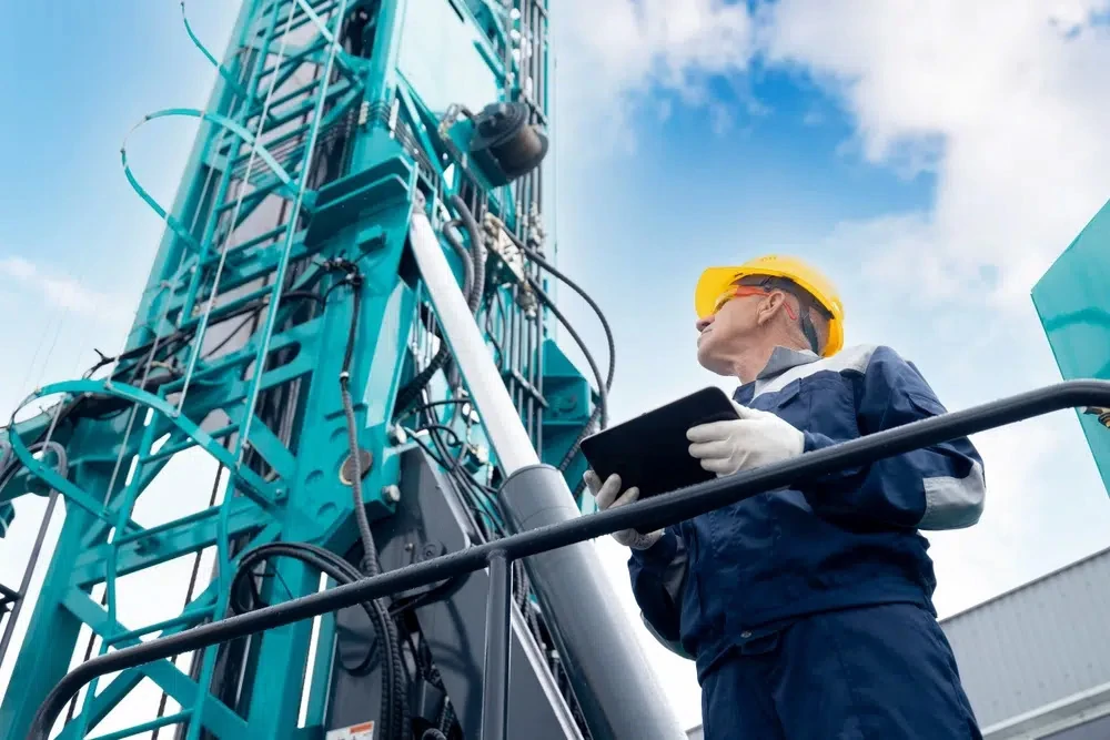 Engineer wearing a yellow hard hat reviewing equipment with a clipboard